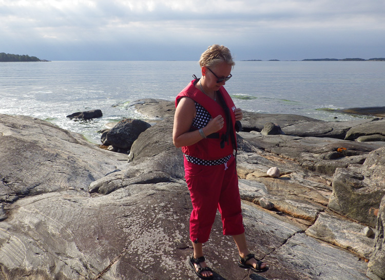 Bild. Eva står på klippstranden. Havet i bakgrunden.