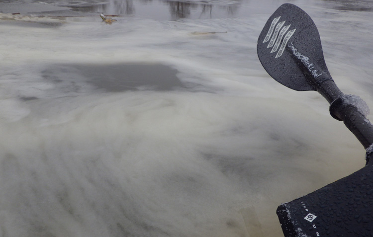 Bild. Fotograferad från kajaken. Snömos samlar sig under vattenytan.