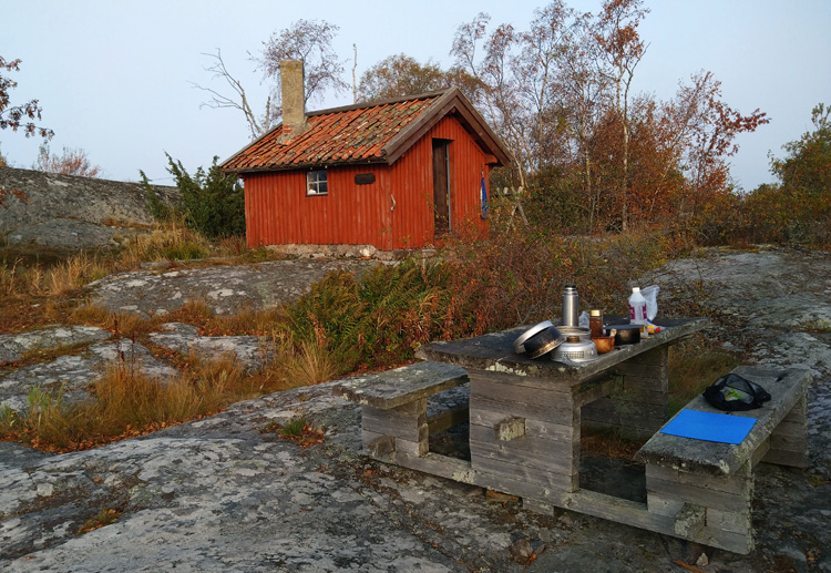 Bild. Stormköket och matlagningsprylar framplockat på bänken framför stugan.